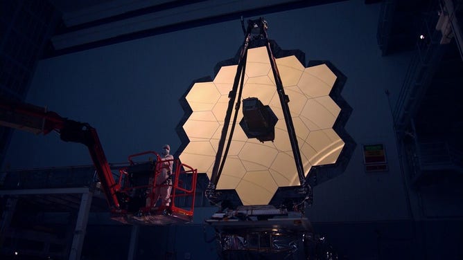 Shown here, the James Webb Space Telescope primary mirror illuminated in a dark cleanroom.