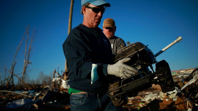 A volunteer carries a toy truck away from a damaged self-srtorage business following a tornado in Dawson Springs, Kentucky, U.S., on Monday, Dec. 13, 2021. President Joe Biden said he will survey tornado damage in Kentucky on Wednesday, after a swarm of twisters swept through the state last week killing dozens. Photographer: Luke Sharrett/Bloomberg via Getty Images