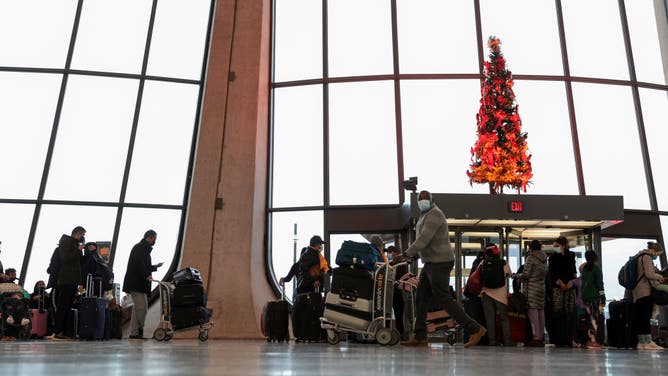 Passengers wait in line to check in for their flights at the Dulles International Airport on December 27, 2021 in Dulles, Virginia. According to media reports, at least 2,600 more flights were canceled Monday amid the surge in coronavirus cases, which have affected the staff within airlines. (Photo by Anna Moneymaker/Getty Images)