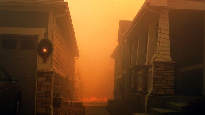 SUPERIOR, CO - DECEMBER 30: A Christmas wreath hangs on the side of a house where fire creeps towards the back on December 30, 2021 in Superior, Colorado. Fierce winds have whipped wildfires in Boulder County. The towns of Superior and Louisville have been evacuated. Multiple homes and businesses have burned from the fast moving fire stocked by fierce winds, with gusts topping 100 mph, along the foothills. The fire has officially been named the Marshall Fire. (Photo by Helen H. Richardson/MediaNews Group/The Denver Post via Getty Images)