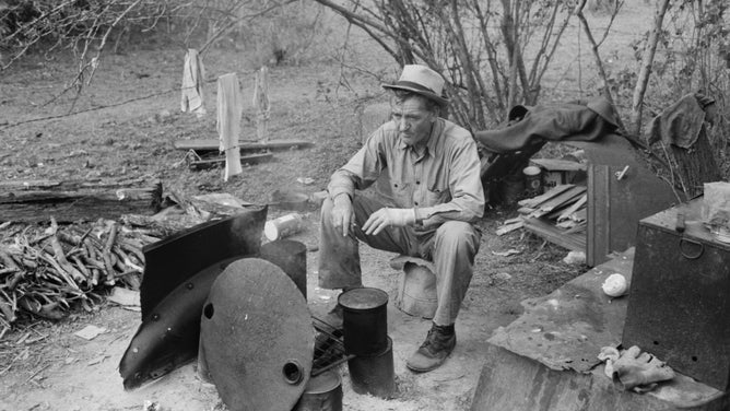 Migrant worker sitting in front of fire in 1939 Harlingen, Texas.