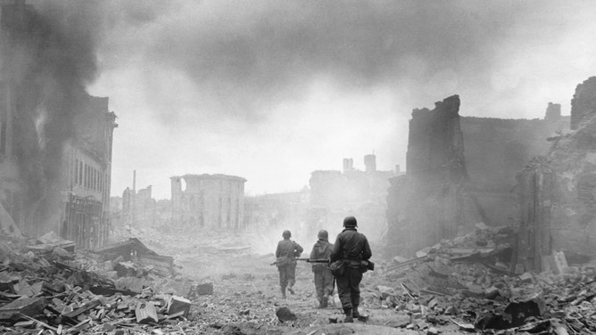 Soldiers walk through a devastated city during WWII.