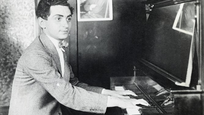 Irving Berlin playing the piano. Berlin wrote a litany of songs and musical scores, such as "White Christmas" and "God Bless America".