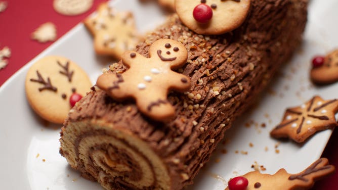 A chocolate yule log cake adorned with cookies in the shape of gingerbread men and reindeer. Some families, especially those of Scandinavian descent, may make yule log cakes during the Christmas holiday season.