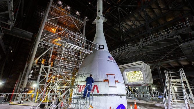 The Artemis I Orion spacecraft, secured on the Space Launch System (SLS) and enclosed in its launch abort system, is in view high up in High Bay 3 of the Vehicle Assembly Building at NASA’s Kennedy Space Center in Florida on Jan. 10, 2022.