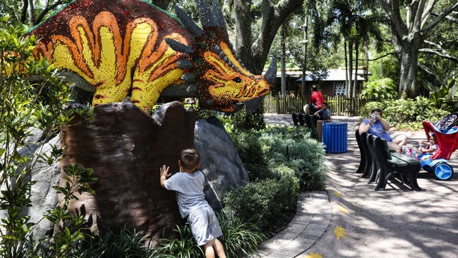 A visitor takes a photograph of a child posing with a Lego sculpture at the Legoland theme park in Winter Haven, Florida, U.S., on Wednesday, June 10, 2020. The $19.3 billion U.S. theme-park industry has been shuttered since March due to the Covid-19 pandemic. Legoland was the first big Florida theme park to reopen after the shut down. Photographer: Eve Edelheit/Bloomberg via Getty Images