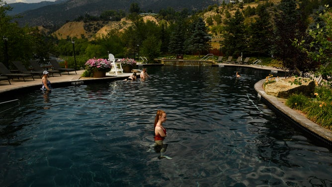 People swim in a pool at Iron Mountain Hot Springs in Colorado. Nestled in the Rocky Mountains, the resort harnessed the hot springs to created soaking pools.