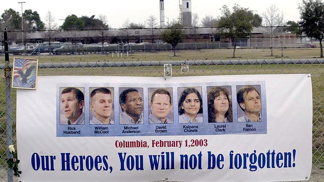 A banner showing the photos of the Columbia space shuttle crew hangs from a fence near a makeshift memorial set up at one of the gates of the Houston Space Center in Houston, Texas, 04 February, 2003. Thousands of sympathizers have left notes, flowers and balloons in memory of the seven Columbia astronauts who perished when the space shuttle desintegrated when re-entering Earth's atmosphere 01 February sixteen minutes before their scheduled landing at the Kennedy Space Center in Florida. AFP PHOTO/James NIELSEN (Photo credit should read JAMES NIELSEN/AFP/GettyImages)