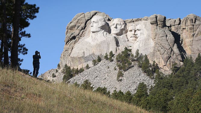 A tourist takes a picture of Mount Rushmore National Memorial from outside the park on October 1, 2013 in Keystone, South Dakota. 