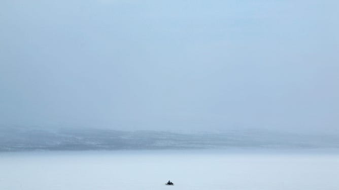 In modern-day Finland, a skiddoo crosses a frozen Lake Kilpisjarvi.