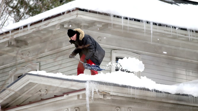 A man clears the roof of a home in Concord, Massachusetts.