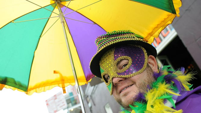 A man with an umbrella poses before a parade on Mardi Gras 2011 in New Orleans.