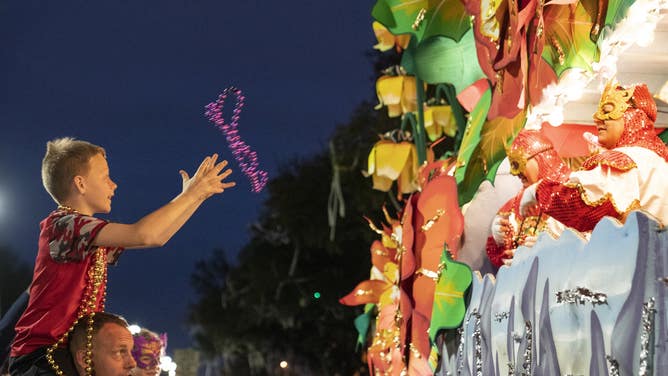 A boy reaches for beads thrown by the 2020 Krewe of Orpheus parade.