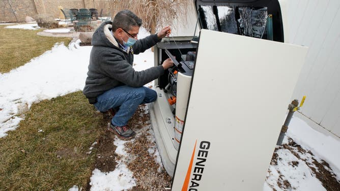 A worker from Captain Electric, makes final inspections on a newly installed 24-kilowatt Generac home generator on February 18, 2021 in Orem, Utah. The company has had a surge in the purchase and installation of home generators over the last several months and currently has a four-month backlog of orders. (Photo by George Frey/Getty Images)