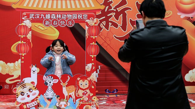 A little girl imitates the ferocity of a tiger on the first day of Lunar New Year.