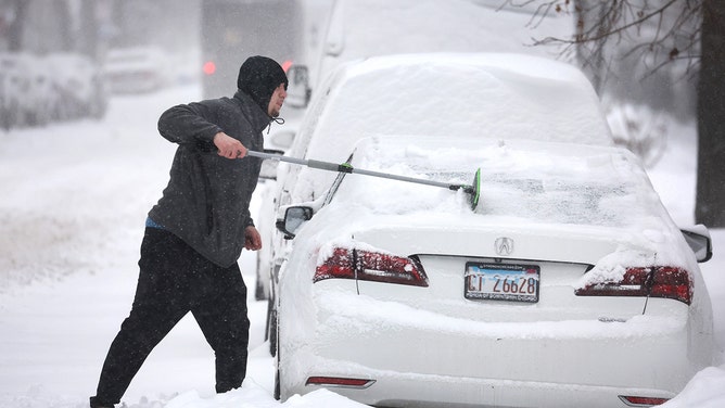A man clears snow from his car on February 02, 2022, in Chicago, Illinois.