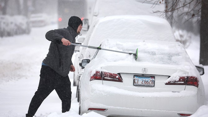 A man clears snow from his car on February 02, 2022, in Chicago, Illinois. 