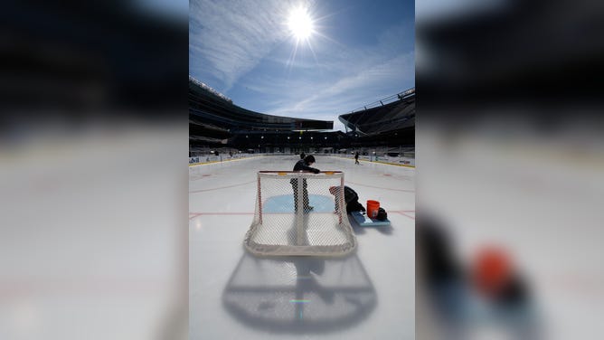 The sun shines over ice crew workers during the 2014 NHL Stadium Series rink build out on February 27, 2014 in Chicago, Illinois.