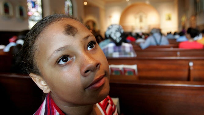 A girl wears a cross of ashes on her forehead prior to Ash Wednesday services in New Orleans.
