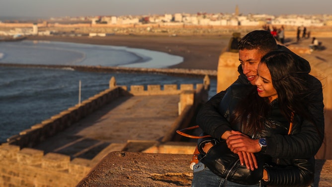 A couple embraces by the beach.