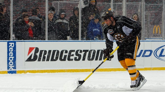 Andrew Ference #21 of the Boston Bruins shovels snow off of the ice during practice prior to Bridgestone's presentation of 2010 NHL Winter Classic at Fenway Park on December 31, 2009 in Boston, Massachusetts.