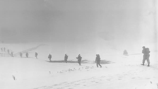 A photograph of soldiers of an Infantry Division moving into the mist toward their objective over a snow-covered field near Krinkelter, Belgium, December 20th, 1944. 