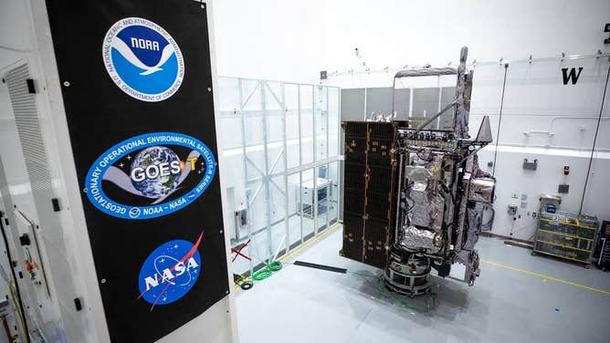 NOAA’s Geostationary Operational Environmental Satellite-T (GOES-T) is in view alongside its banner inside the Astrotech Space Operations facility in Titusville, Florida, on Jan. 20, 2022. GOES-T is scheduled to launch on March 1, 2022, atop a United Launch Alliance (ULA) Atlas V 541 rocket from Space Launch Complex 41 at Cape Canaveral Space Force Station.
