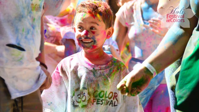 Covered in colored powder, a young Festival of Colors attendee grins from ear to ear.