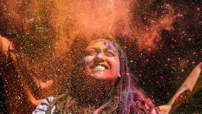 Holi celebrants throw colored powder in the air, a signature component of Holi.