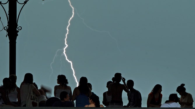 People take shelter as a lightning strikes in Revere Beach, Massachusetts.