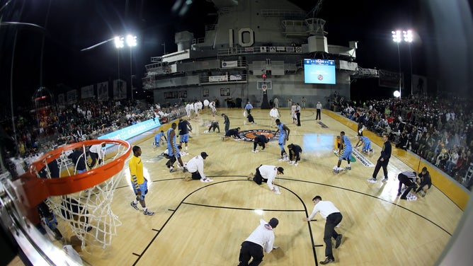Members of the Military as well as players from the Marquette Golden Eagles and the Ohio State Buckeyes attempt to dry condensation off of the court which caused a delay to the start of their game during the Walmart Carrier Classic played on the deck of the USS Yorktown on November 9, 2012 in Charleston, South Carolina. 