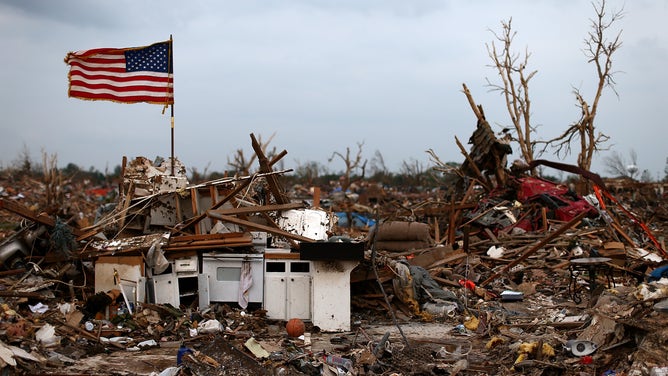An American flag flies over the rubble of a destroyed neighborhood on May 24, 2013 in Moore, Oklahoma. The tornado of EF5 strength and two miles wide touched down May 20 killing at least 24 people.