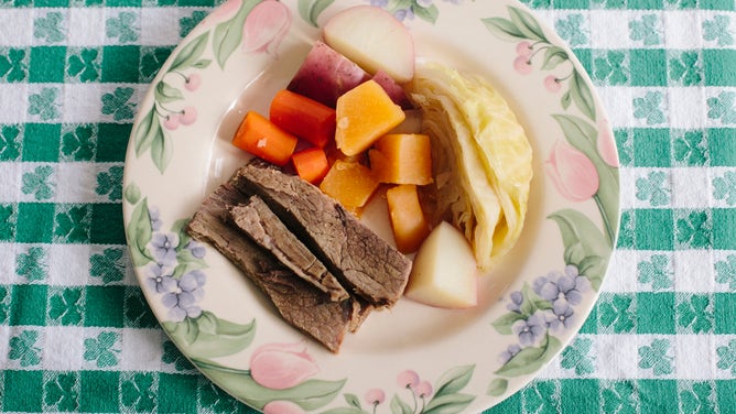 A plate of corned beef and cabbage, set on a shamrock-patterned tablecloth.