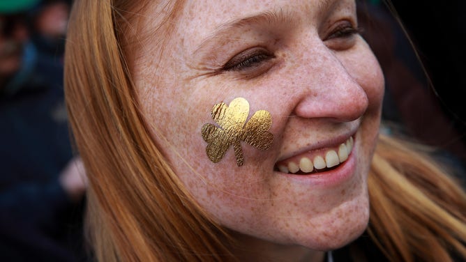 A St. Patrick's Day parade spectator wears a golden shamrock painted on her cheek.