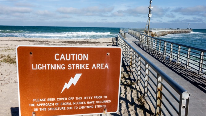 A caution lightning strike area sign next to the fishing pier at Sebastian Inlet State Park in Florida.