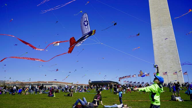 At the foot of the Washington Monument, a boy flies his airplane-shaped kite. He and many others have gathered at the National Cherry Blossom Festival's Kite Festival in Washington, D.C.