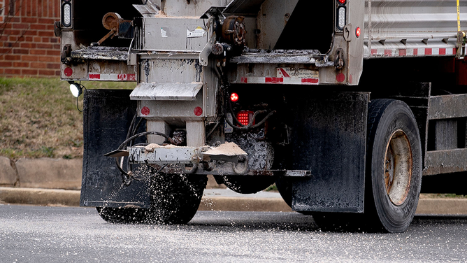 A snowplow salts and sands a street in Washington, DC, on January 16, 2022, ahead of a winter storm.