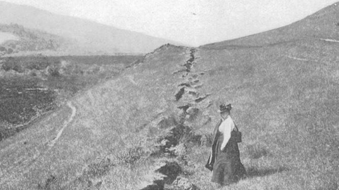 A woman stands next to a fault trace near Point Reyes Station, which is located northwest of downtown San Francisco.