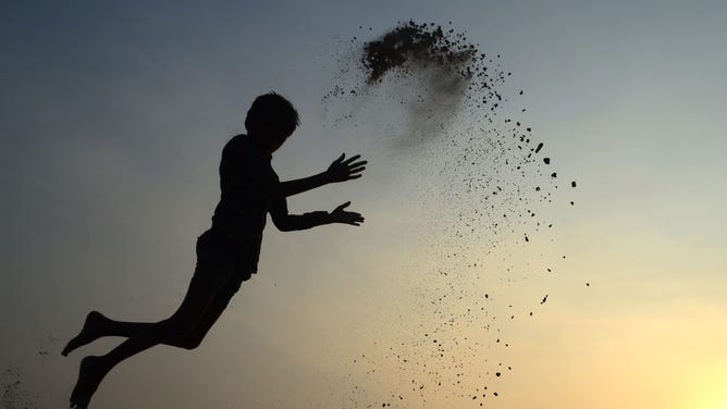 A boy in mid-air at sunset.