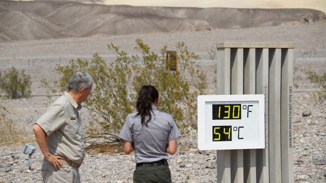 Park staff takes pictures of a thermometer display showing 130 Degrees Fahrenheit (54 Degrees Celsius) at the Furnace Creek Visitor's Center at Death Valley National Park on June 17, 2021, in Furnace Creek, California.