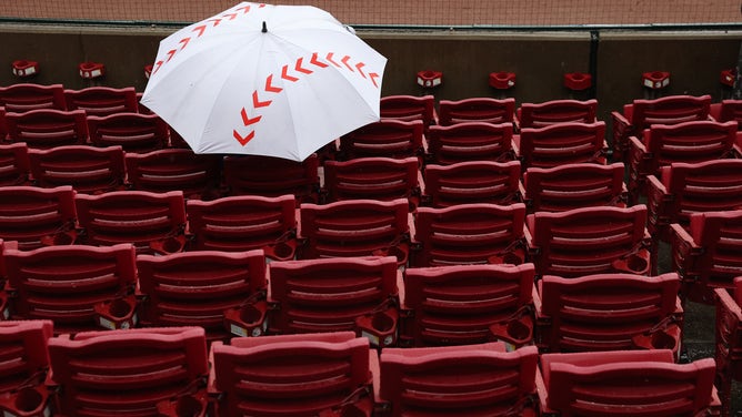 Fans shelter from the rain under a baseball-shaped umbrella at Great American Ball Park on September 22, 2021 in Cincinnati, Ohio.