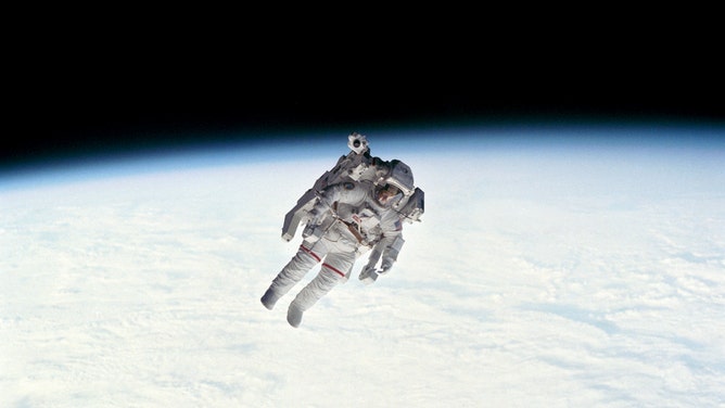 An astronaut floats above the Earth.