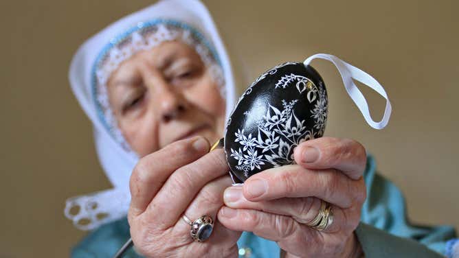 A woman in the Czech Republic wears a traditional costume while decorating Easter eggs.