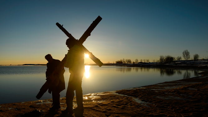 A parishioner and church usher carry a cross from the beach after the 21st annual Easter sunrise celebration service on March 27, 2016 in Boulder, Colorado.