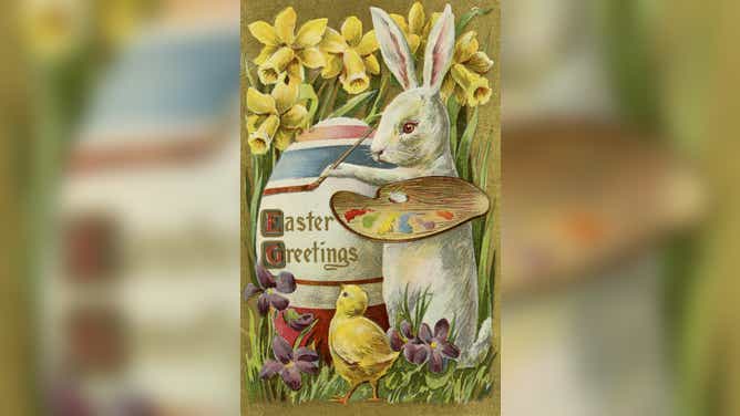 In this Easter postcard, an Easter bunny paints an Easter egg as a baby chick watches below.