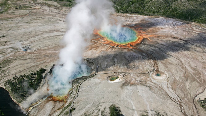 An aerial photograph of Excelsior Geyser and Grand Prismatic Spring in the Midway Geyser Basin, Yellowstone National Park, Wyoming.