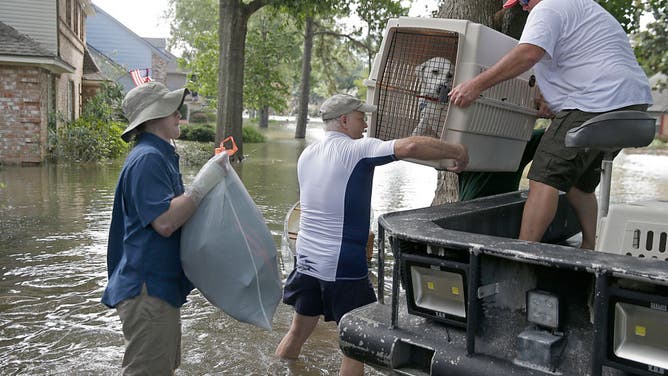 A father and son carry their dog as they evacuate from their homes the flood in Lakeside Estate in Houston, Texas on August 30, 2017. - Monster storm Harvey made landfall again Wednesday in Louisiana, evoking painful memories of Hurricane Katrina's deadly strike 12 years ago, as time was running out in Texas to find survivors in the raging floodwaters. (Photo by Thomas SHEA / AFP) (Photo by THOMAS SHEA/AFP via Getty Images)