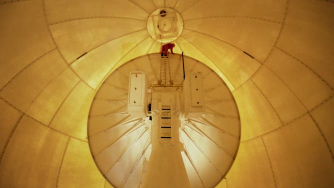 An employee is seen at the top of the weather radar within the radome. 