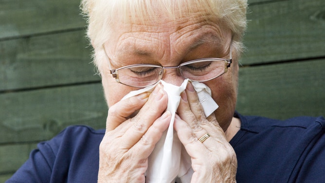 Woman blowing her nose.