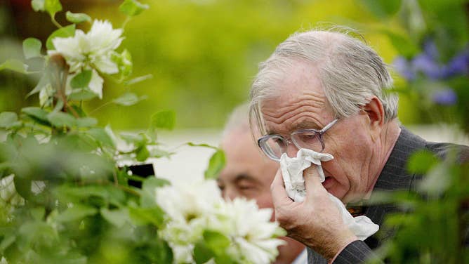A man covers his nose while sneezing.